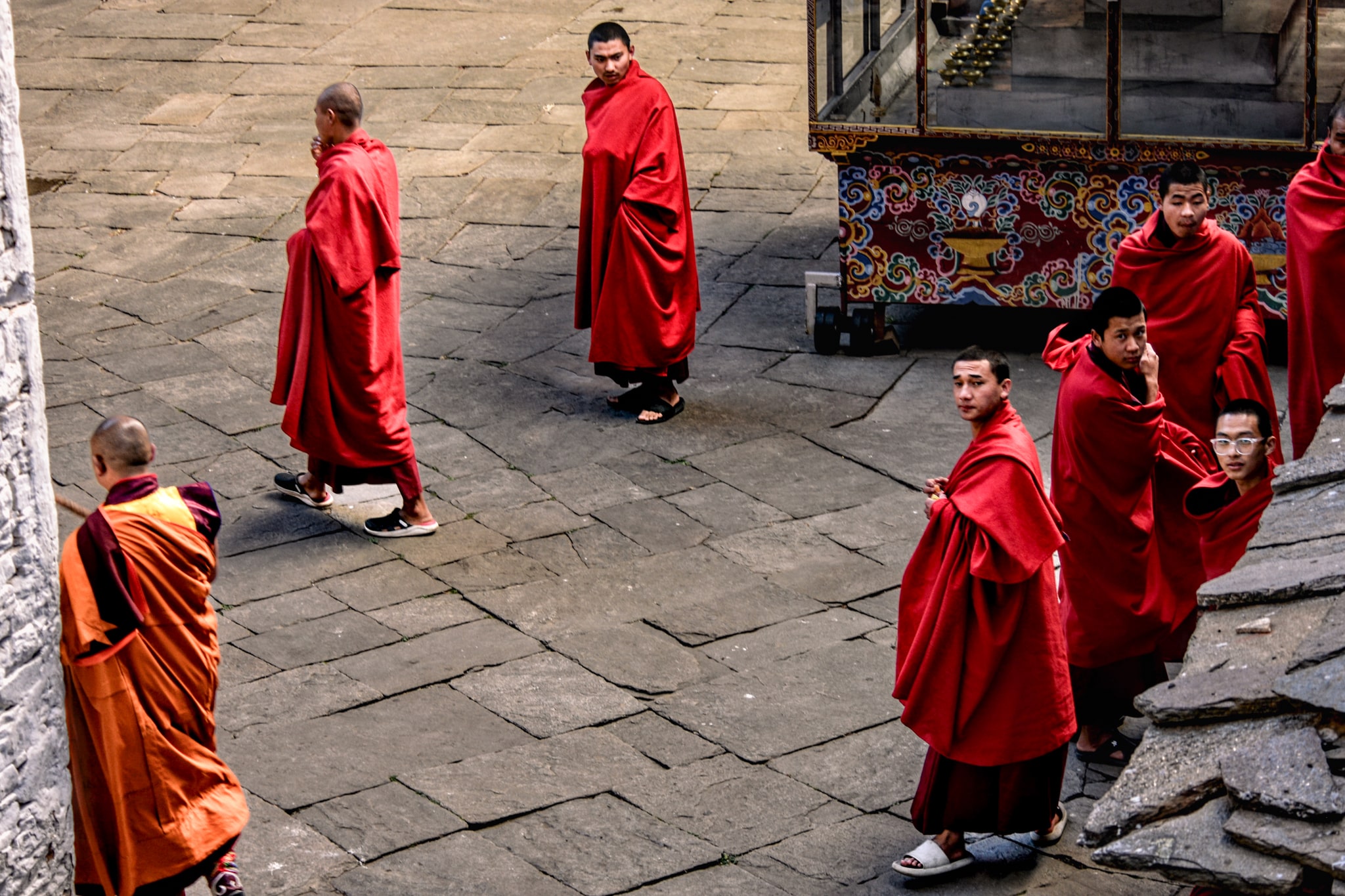 Groups of monks in traditional red ropes walking in Bhutan.